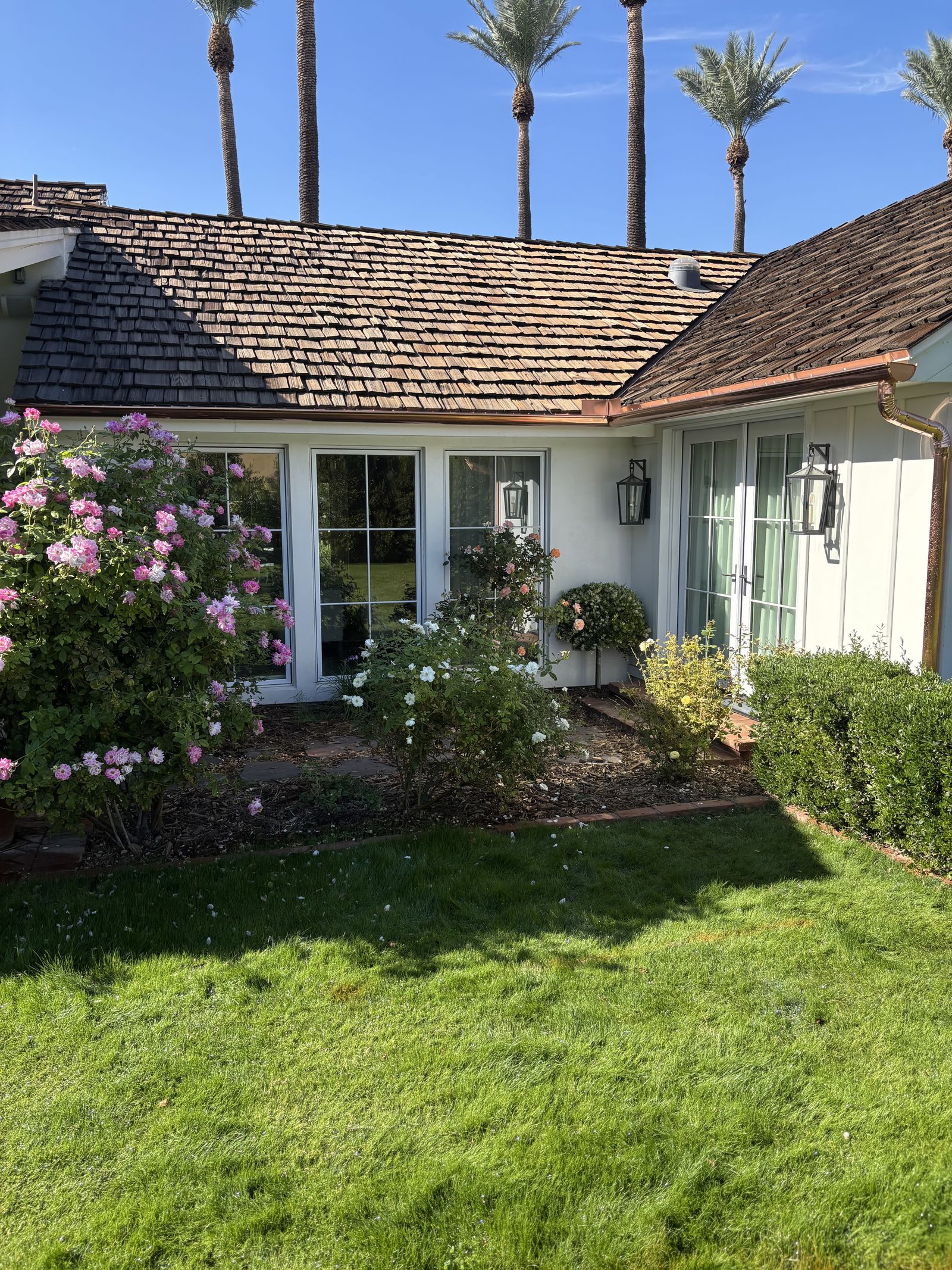 Copper gutter and downspout on estate home with palms and lawn — Grizzly Rain Gutters