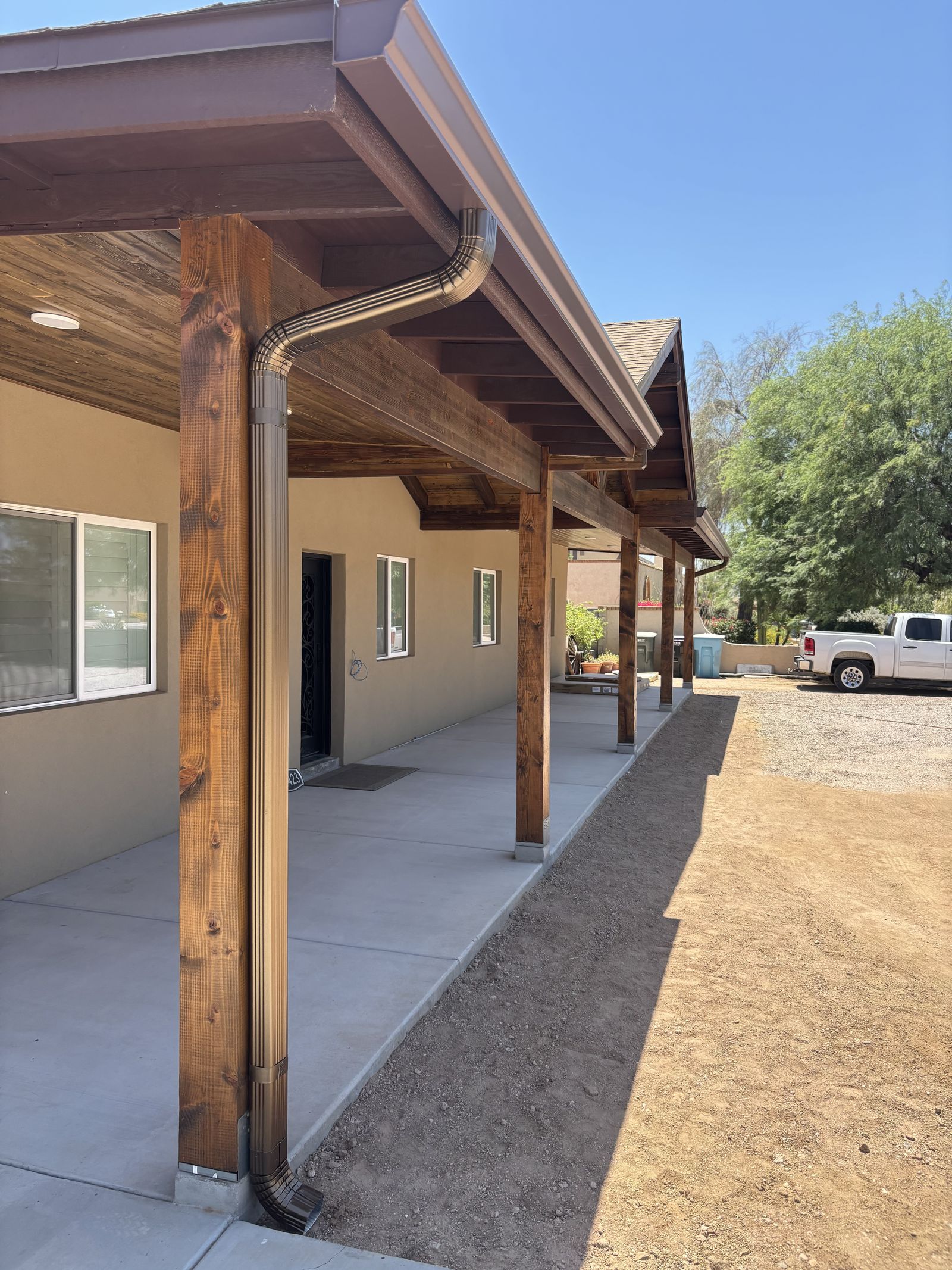 Bronze-tone aluminum gutter on covered patio with downspout — Grizzly Rain Gutters