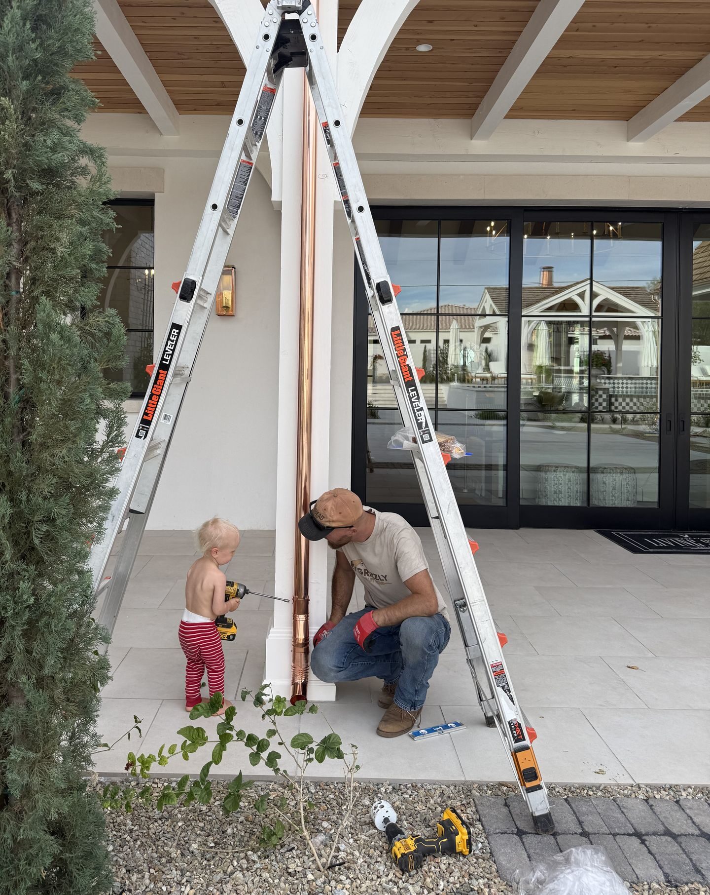 Grizzly Gutters crew securing copper downspout at estate entry — authentic job photo
