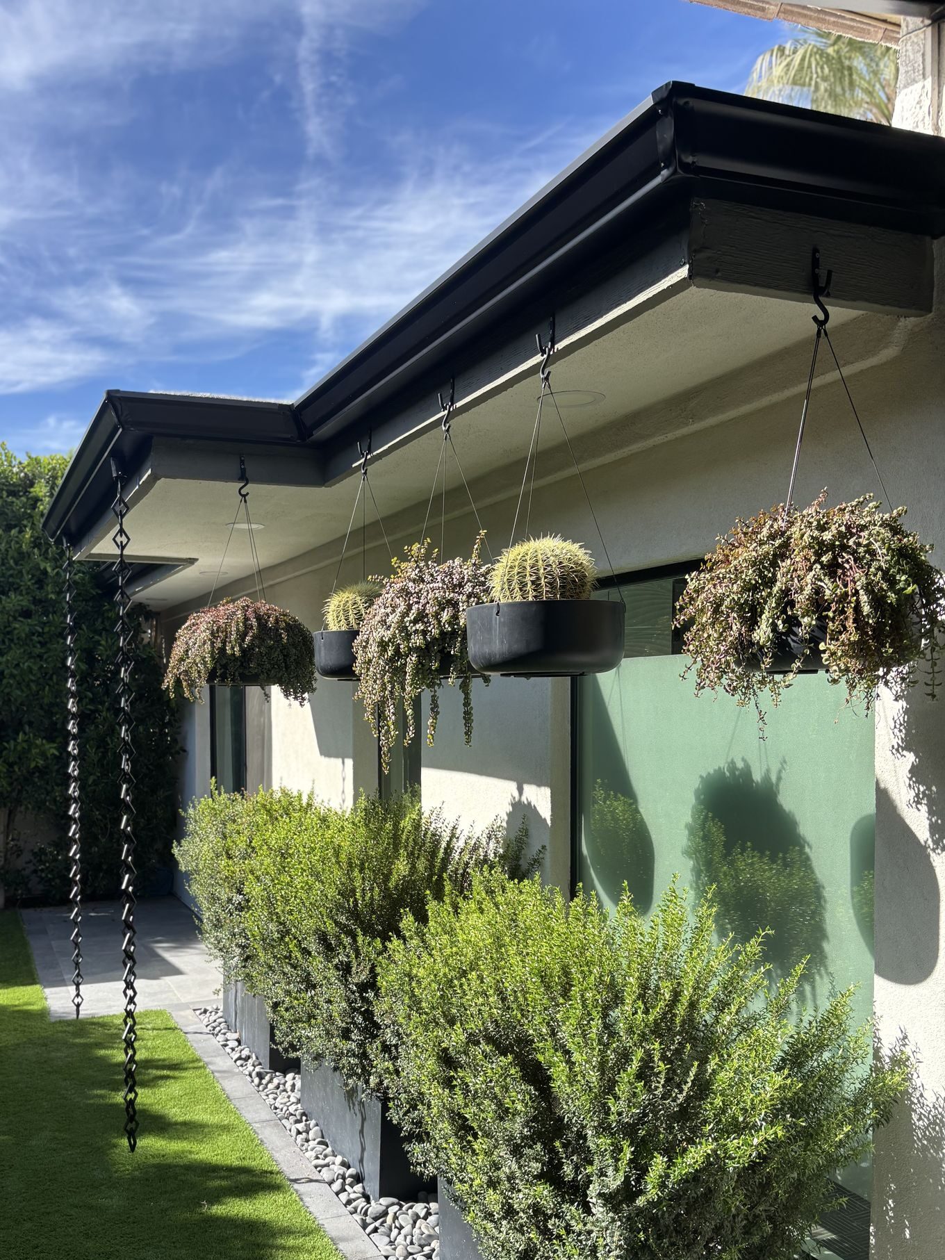 Black gutter with rain chains in side yard garden — Grizzly Rain Gutters