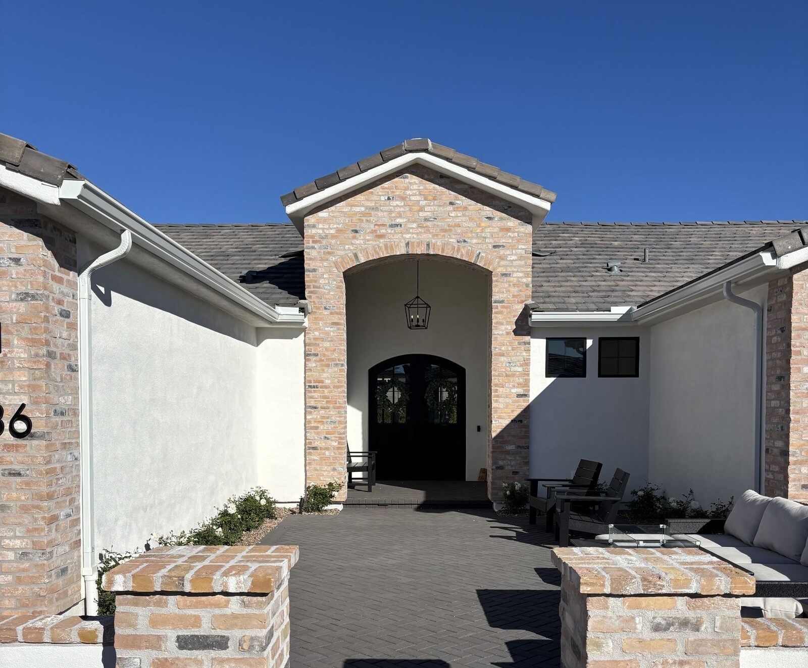 White aluminum gutters on brick-and-stucco entry courtyard — Grizzly Rain Gutters Phoenix